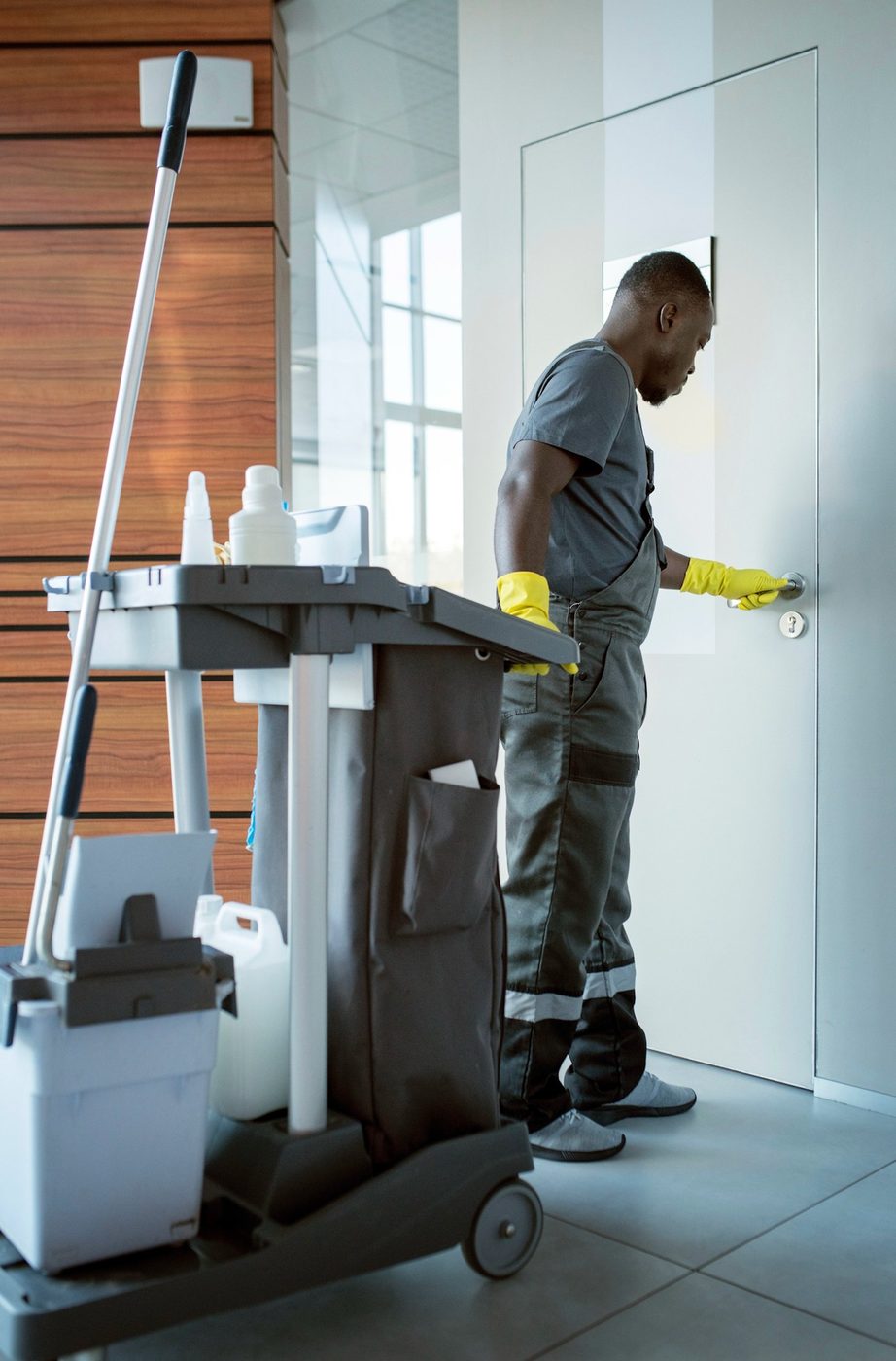 Office cleaner sanitising a door handle and high-touch points in Birmingham
